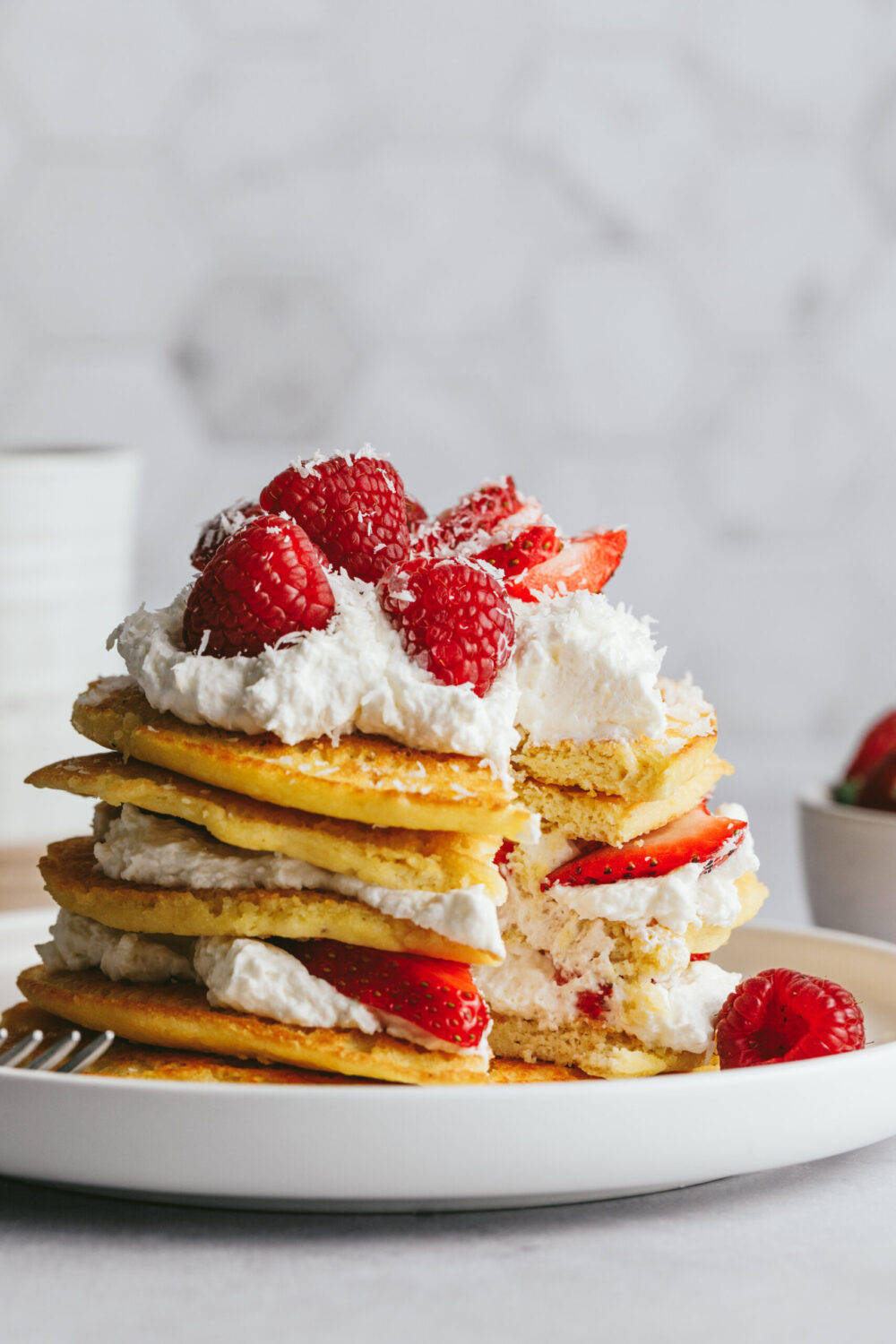 Low-carb pancakes styled in a stack with fresh berries and whipped cream.