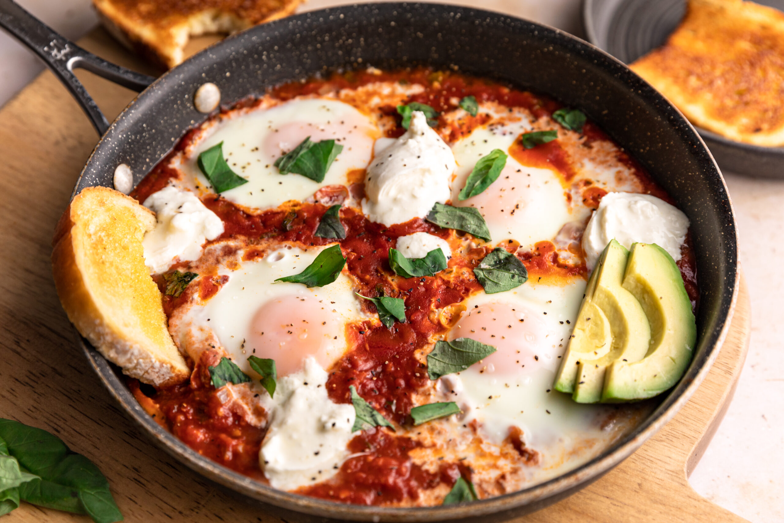 Low-carb shakshouka in a pan with avocado and burrata on top.